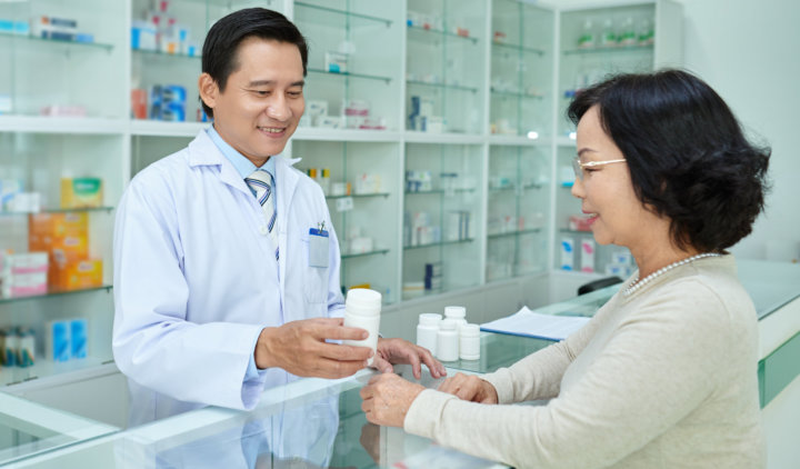 pharmacist giving a medicine to a female customer at the counter