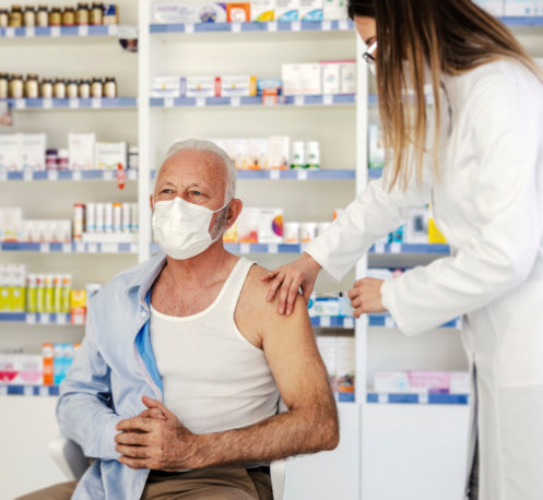 nurse giving covid vaccine to an old man at pharmacy