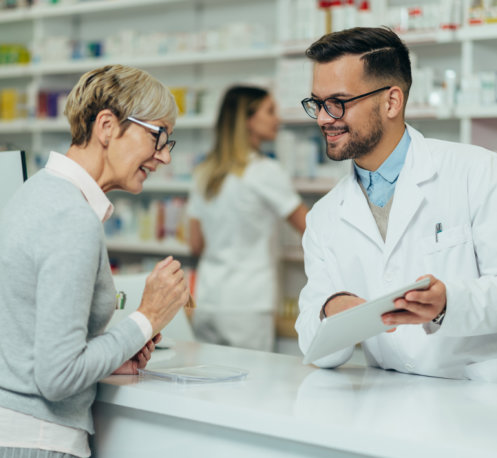 pharmacist giving prescription medications to senior female customer