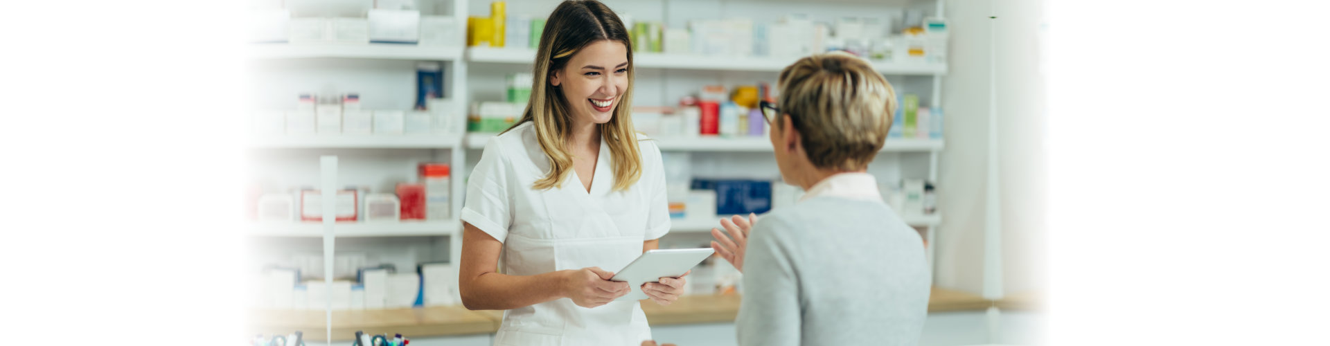 female pharmacist selling medications at drugstore to a senior woman customer